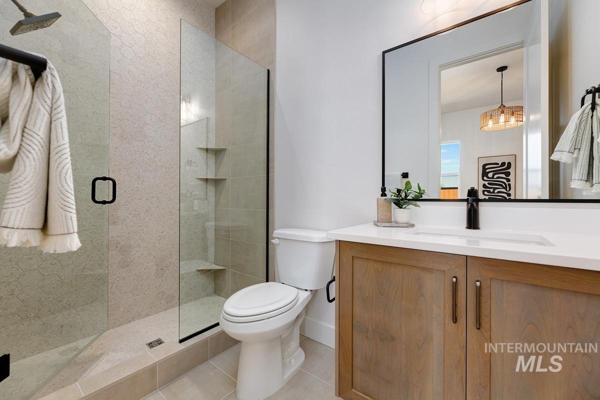 Bathroom featuring vanity, a stall shower, light tile patterned floors, and a chandelier