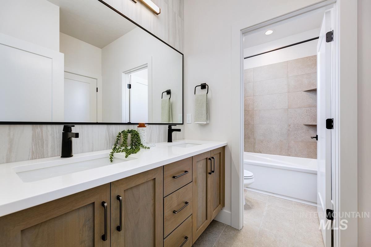 Bathroom featuring double vanity, shower / bathtub combination, and light tile patterned floors