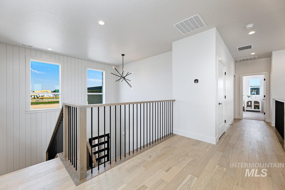 Corridor featuring a chandelier, recessed lighting, light wood-style flooring, and an upstairs landing