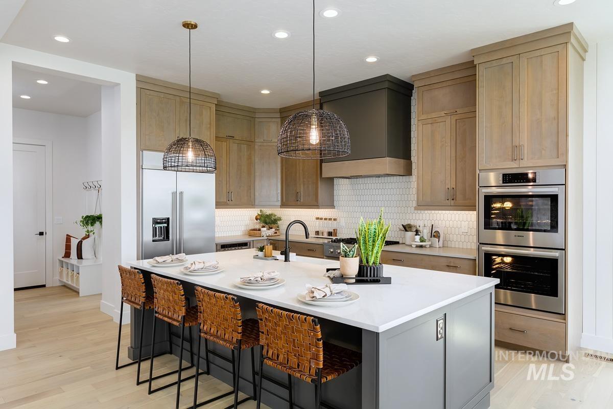 Kitchen featuring decorative backsplash, a breakfast bar, appliances with stainless steel finishes, pendant lighting, and recessed lighting