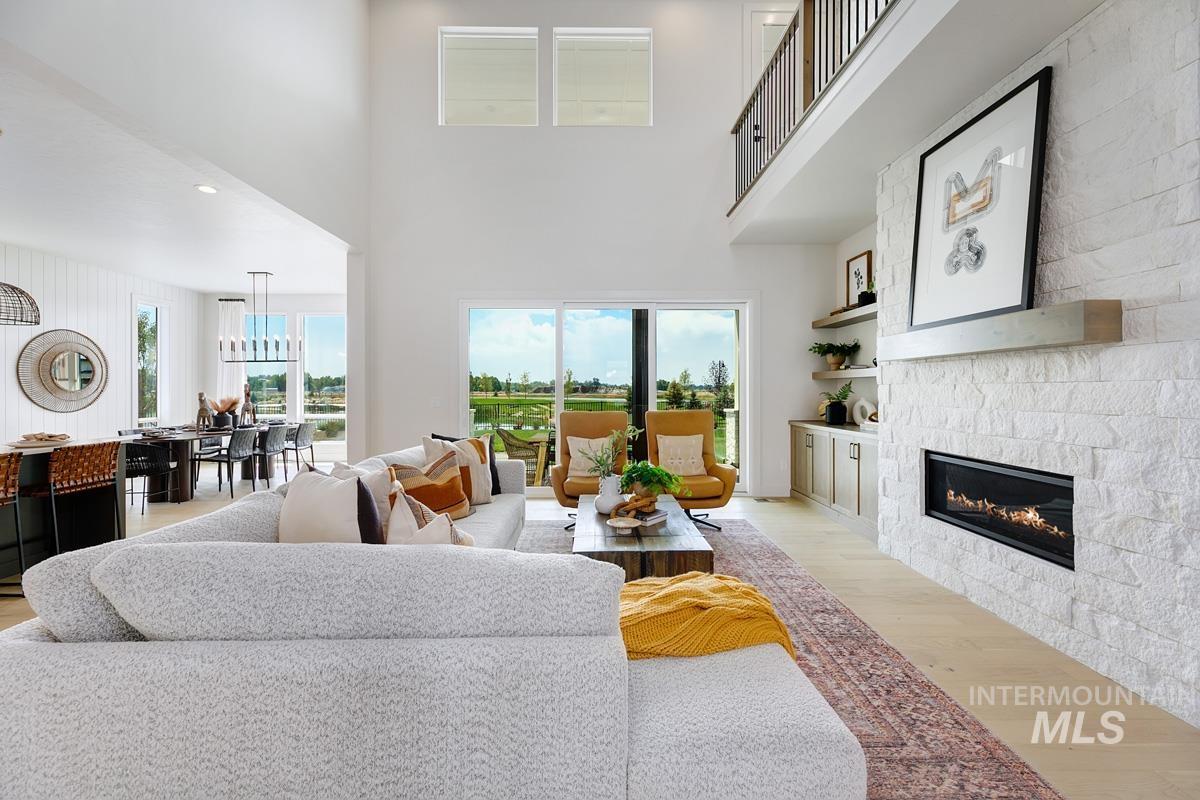 Living area featuring light wood finished floors, a high ceiling, recessed lighting, and a glass covered fireplace