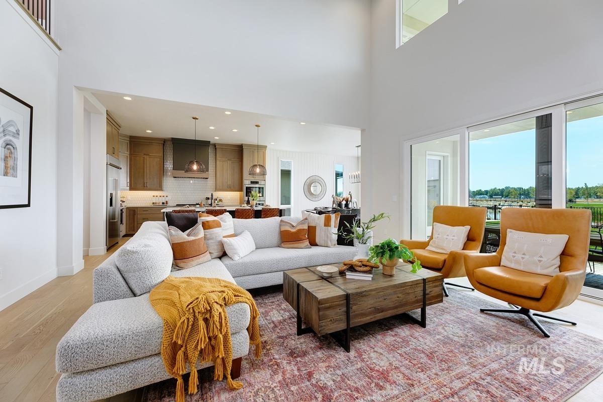 Living room with light wood-type flooring, a high ceiling, and recessed lighting