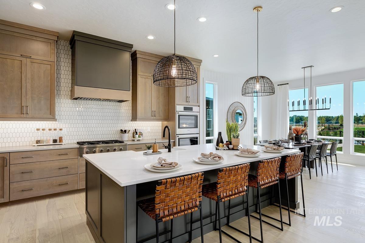 Kitchen with plenty of natural light, tasteful backsplash, light stone countertops, recessed lighting, and decorative light fixtures