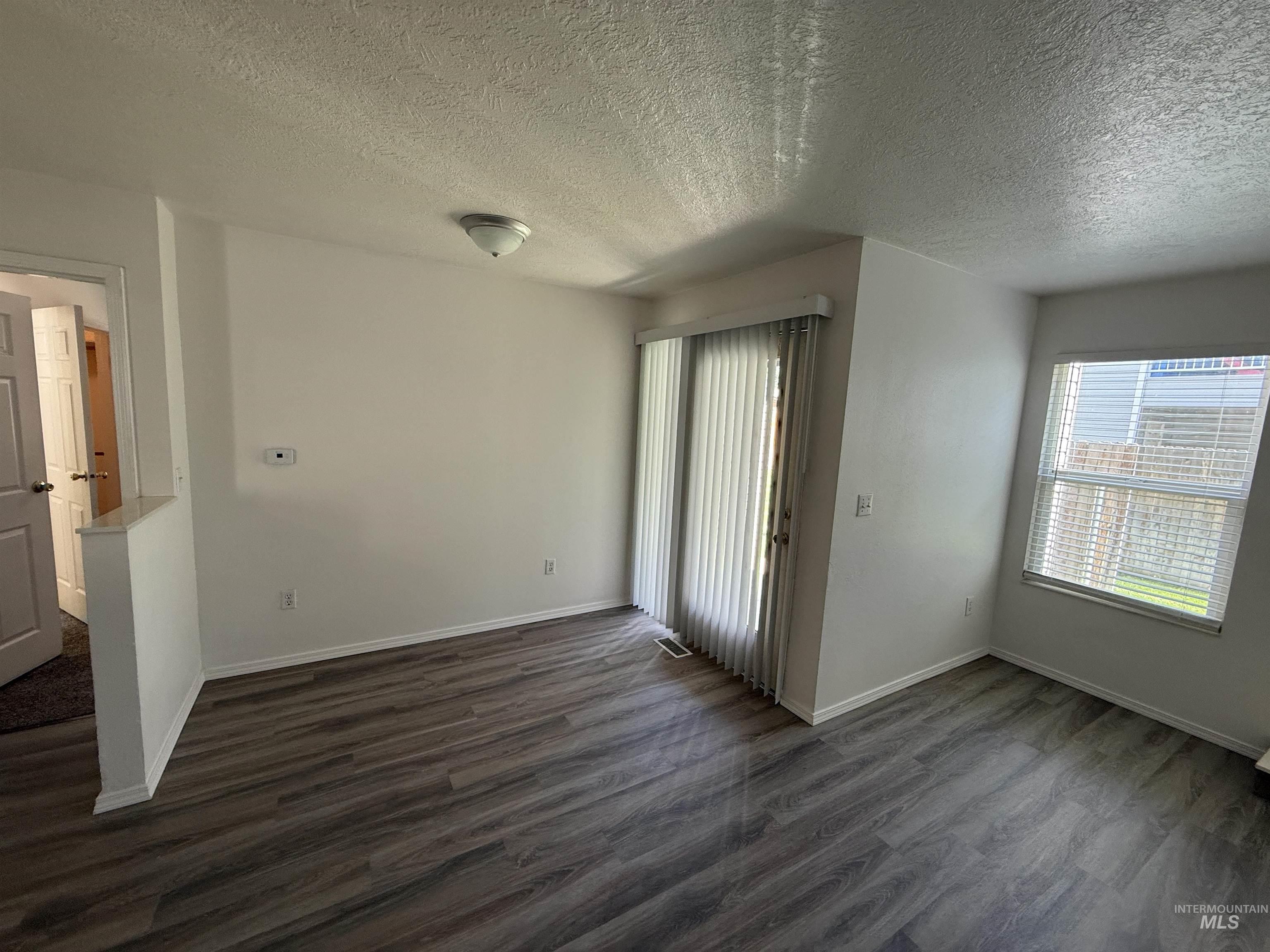Unfurnished room with dark wood finished floors and a textured ceiling