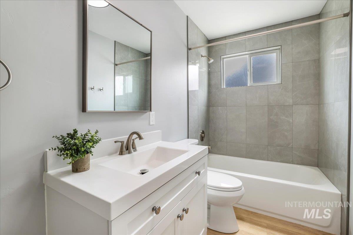 Bathroom featuring  shower combination, vanity, and light wood-type flooring