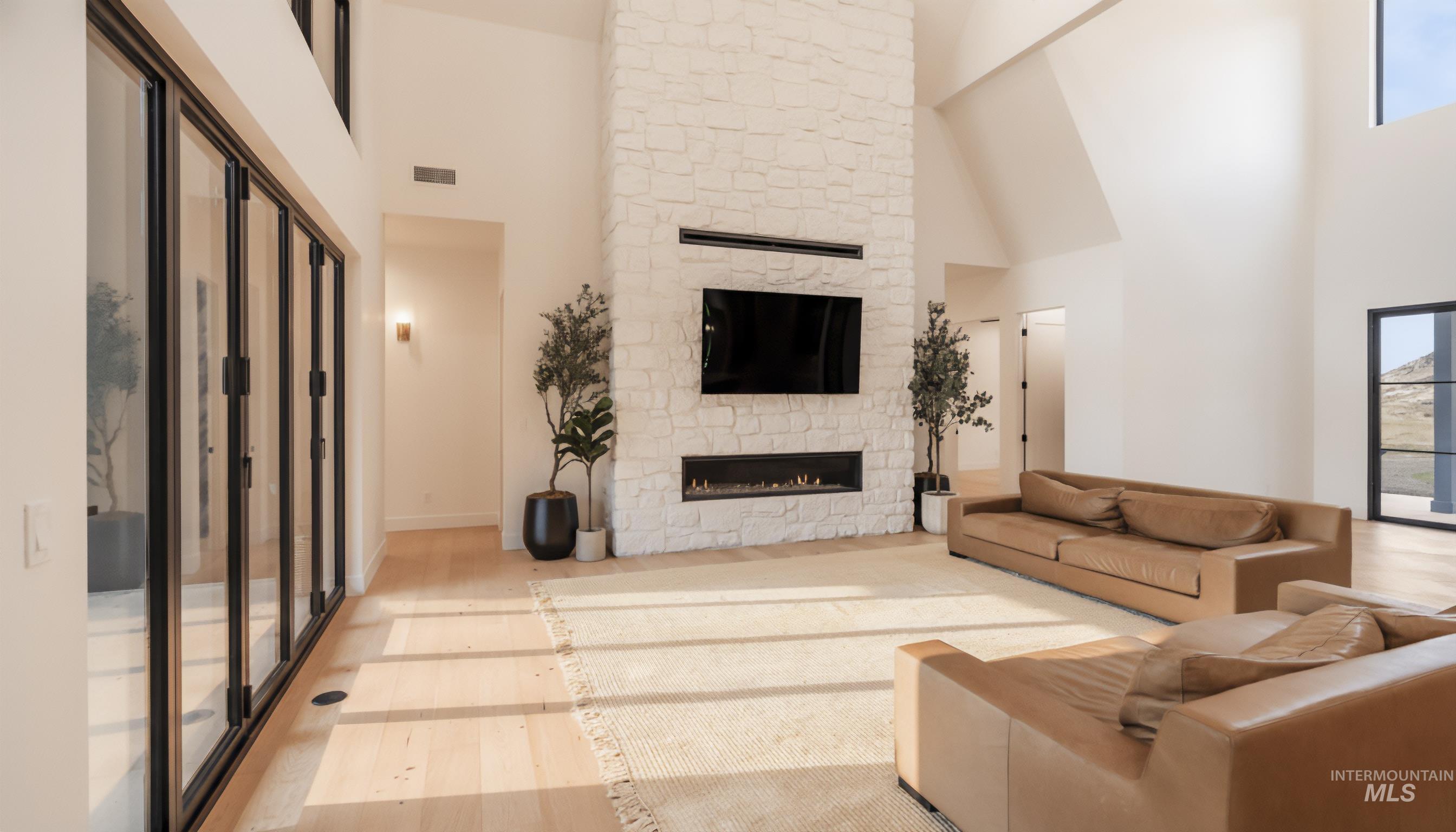 Living area with a towering ceiling, a fireplace, healthy amount of natural light, and wood finished floors
