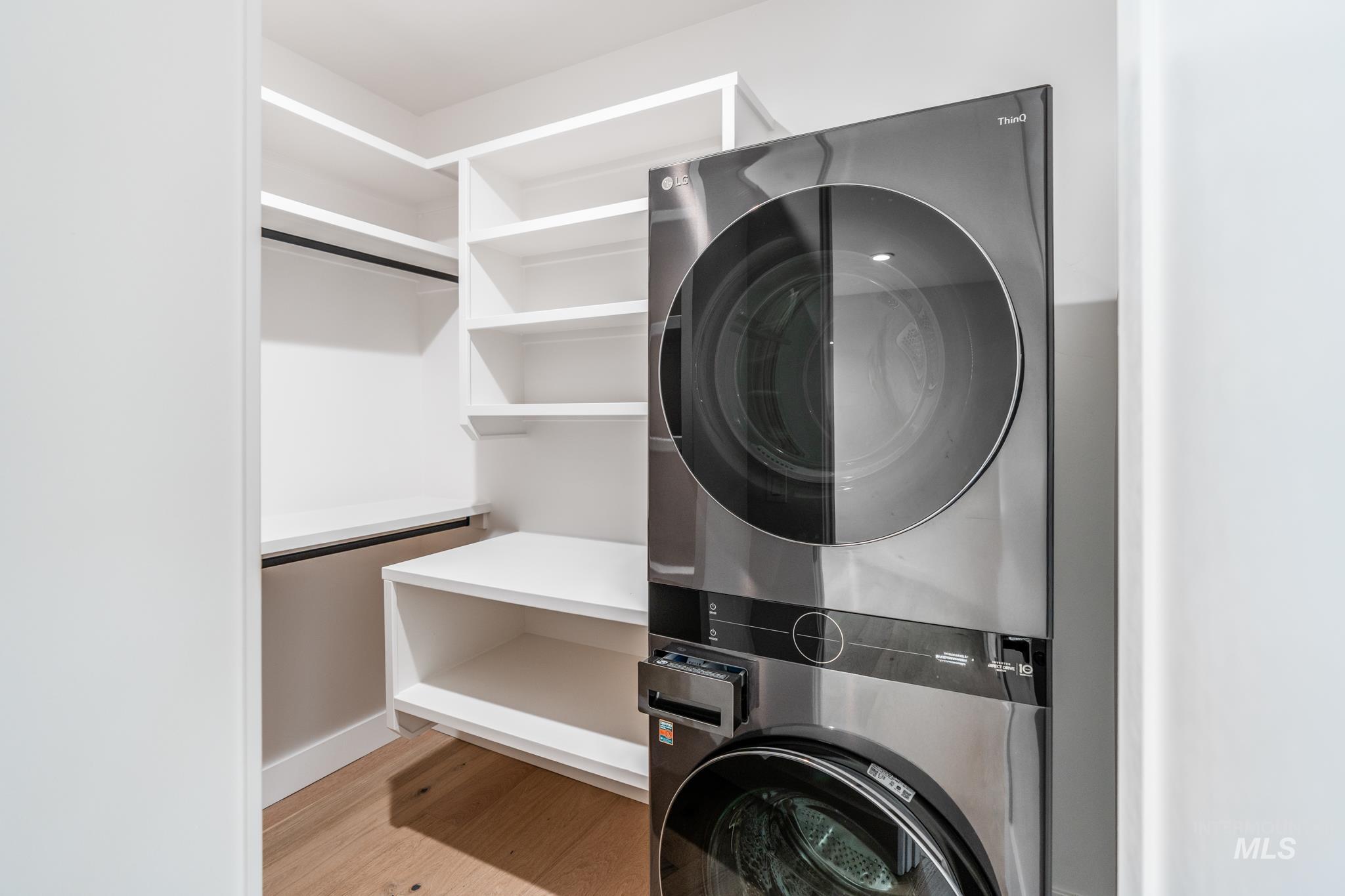 Laundry room with light wood-style floors and estacked washer and dryer