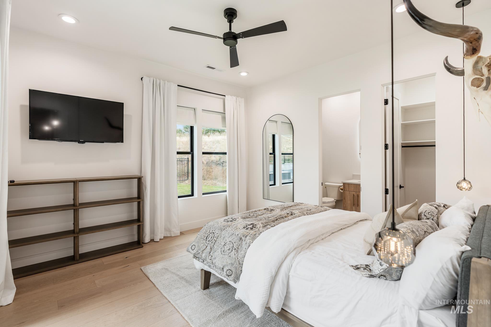 Bedroom with light wood-style floors, a ceiling fan, ensuite bathroom, and recessed lighting