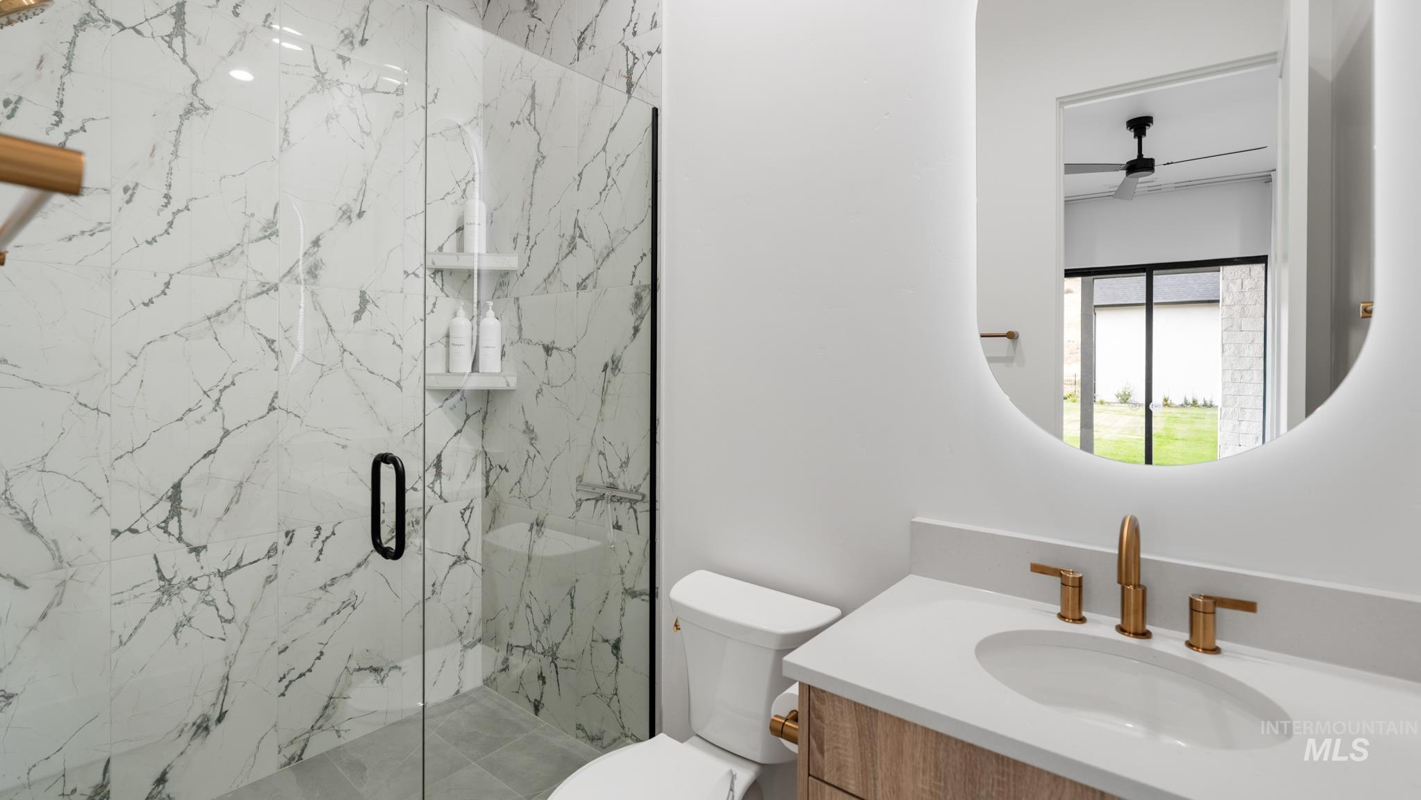 Full bathroom with vanity, a marble finish shower, and ceiling fan