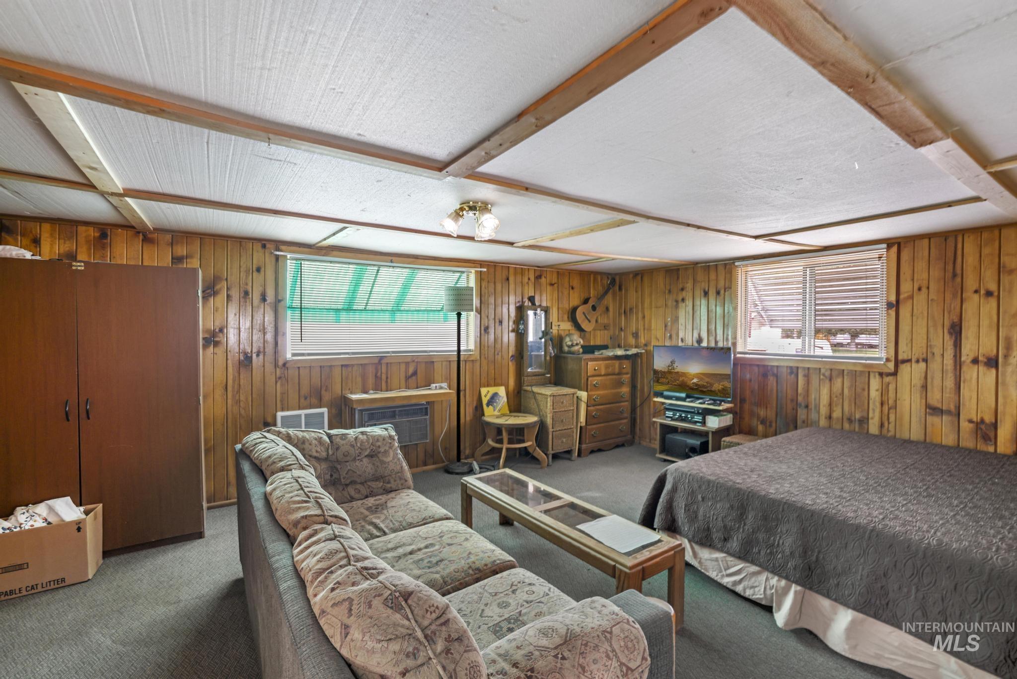 Carpeted bedroom with wooden walls and multiple windows