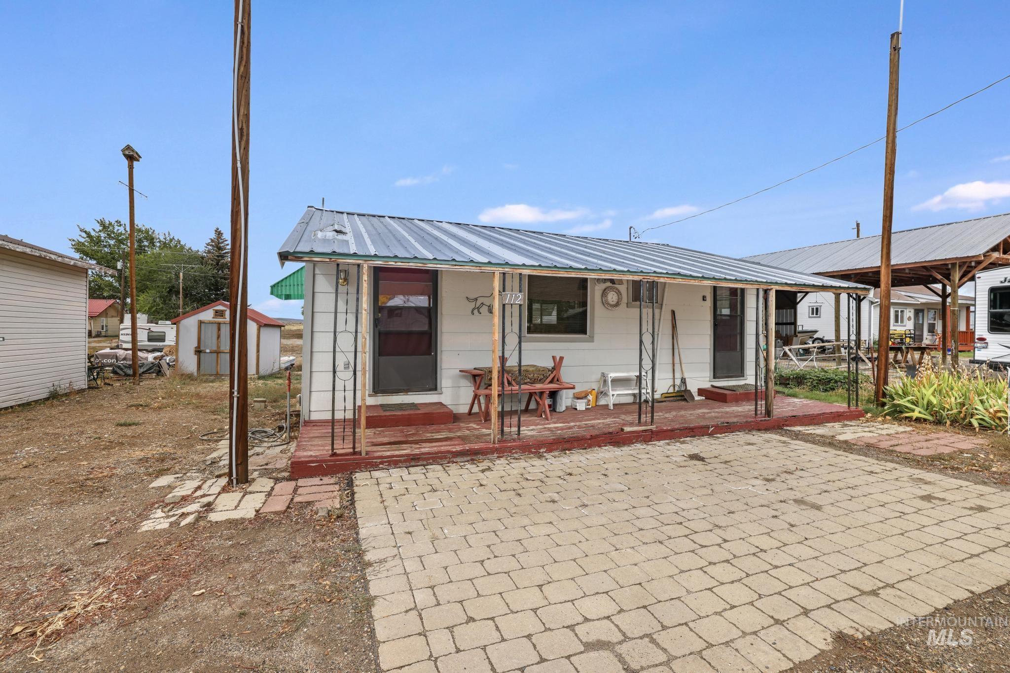 View of front of property with a metal roof, a larger storage shed, and a patio