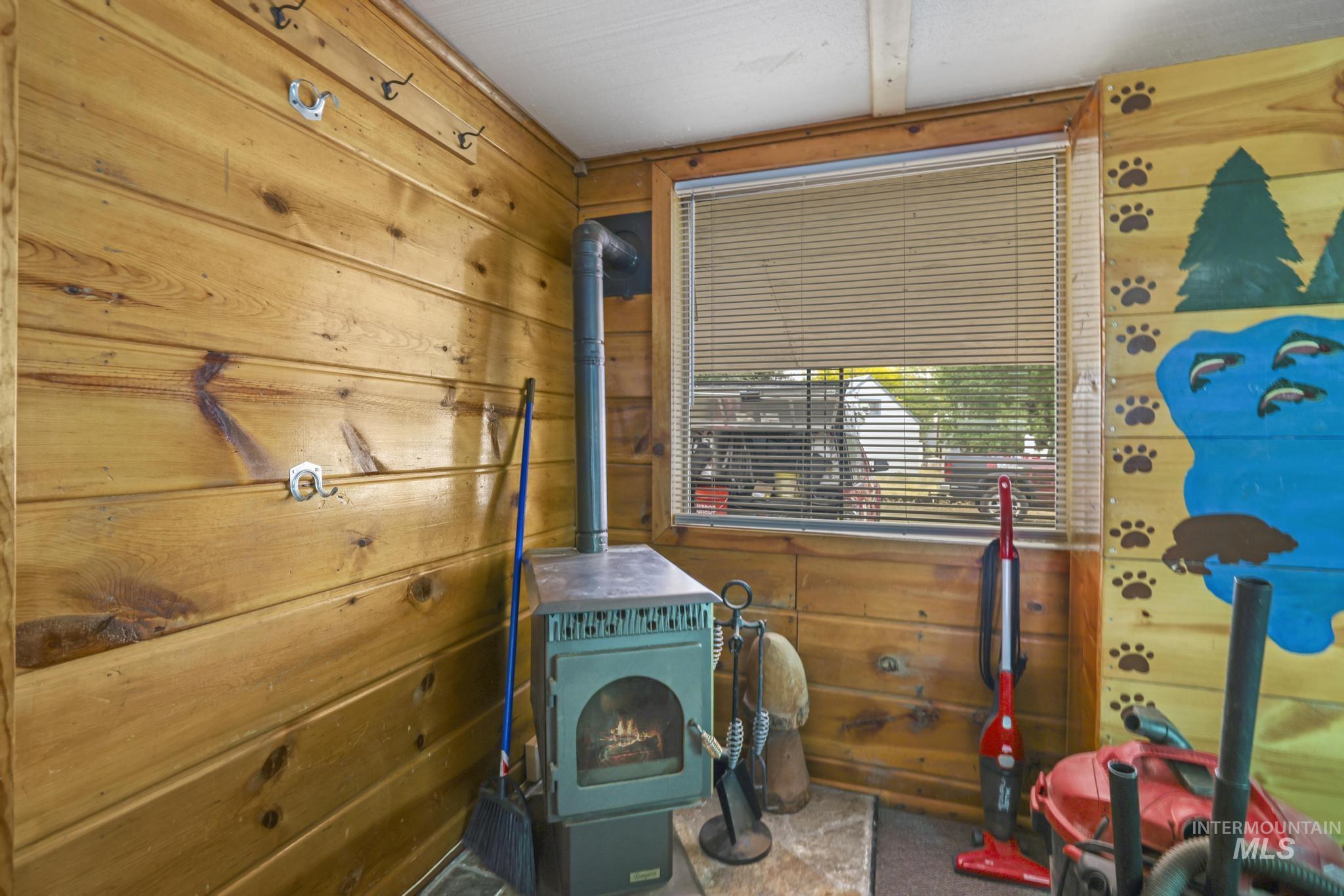 Laundry room with wooden walls, a pellet stove, and carpet flooring