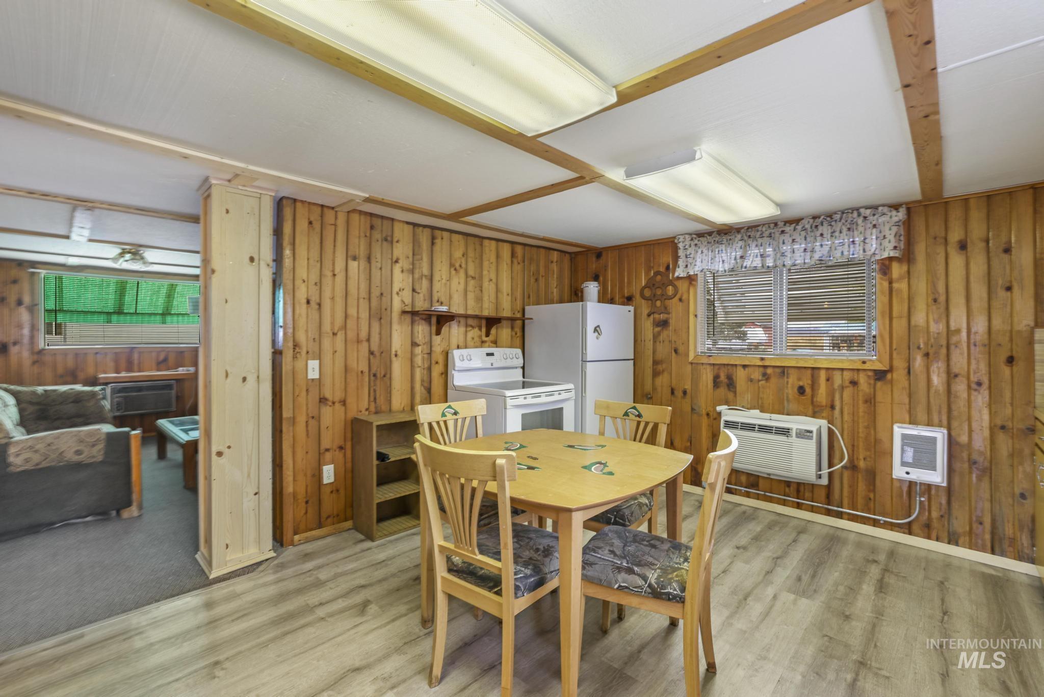 Dining area featuring wooden walls, heating unit, and light wood-style flooring