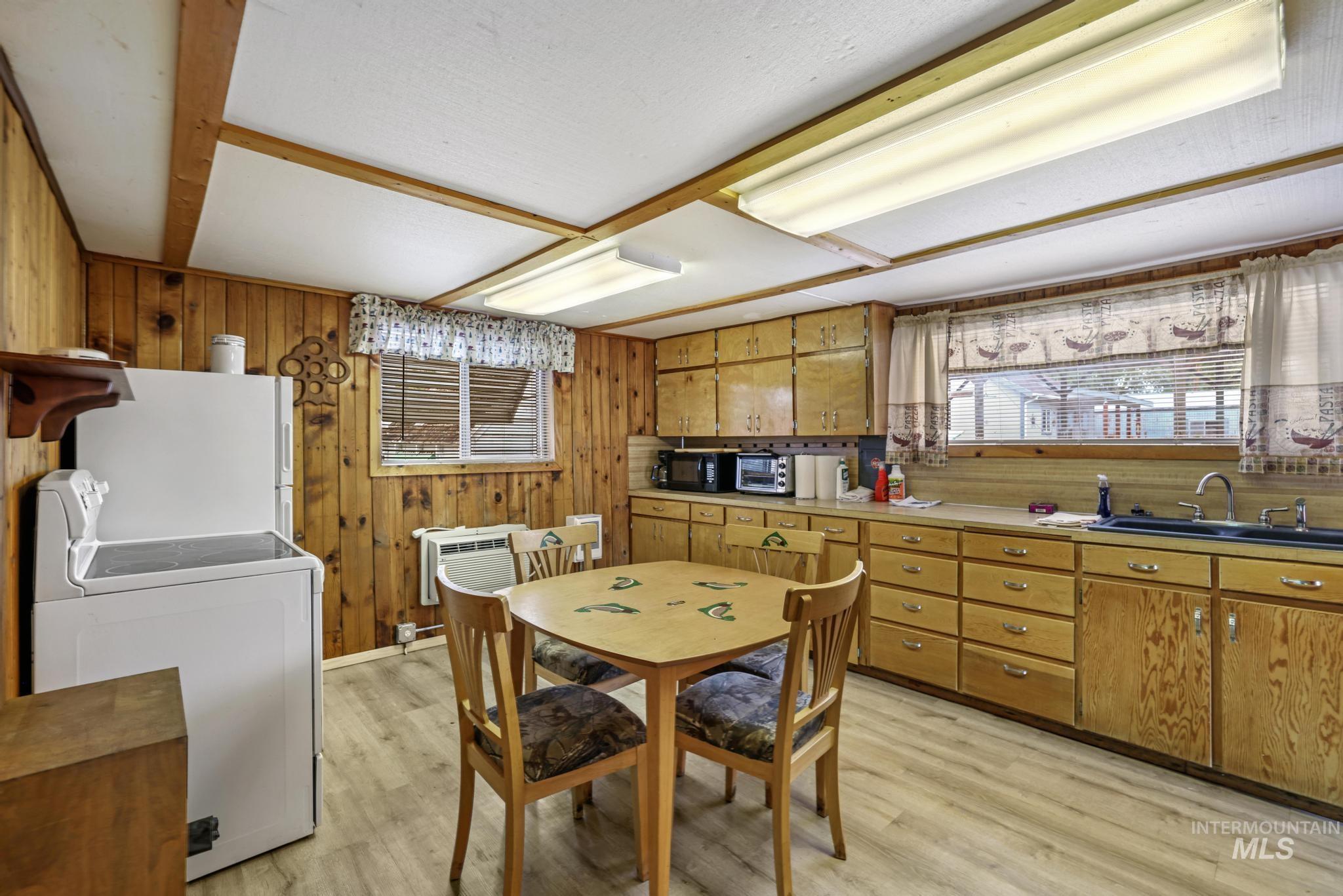 Dining space with wood walls, light wood-style flooring, a wall mounted AC