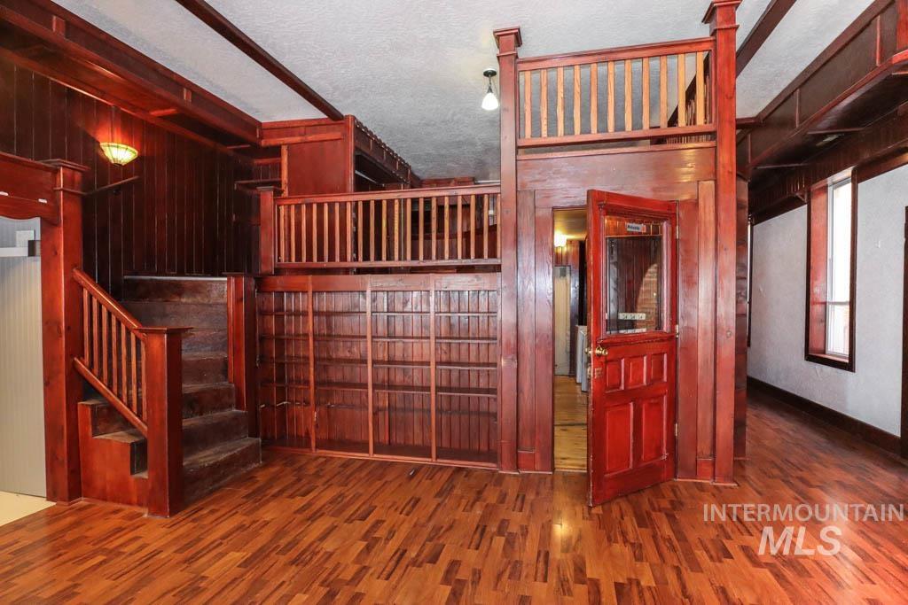 Staircase featuring a textured ceiling, wood walls, and wood finished floors