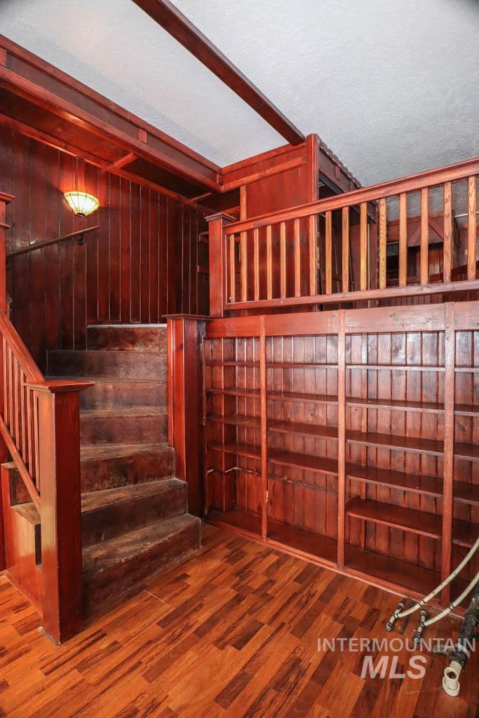 Stairway featuring wood finished floors and wooden walls