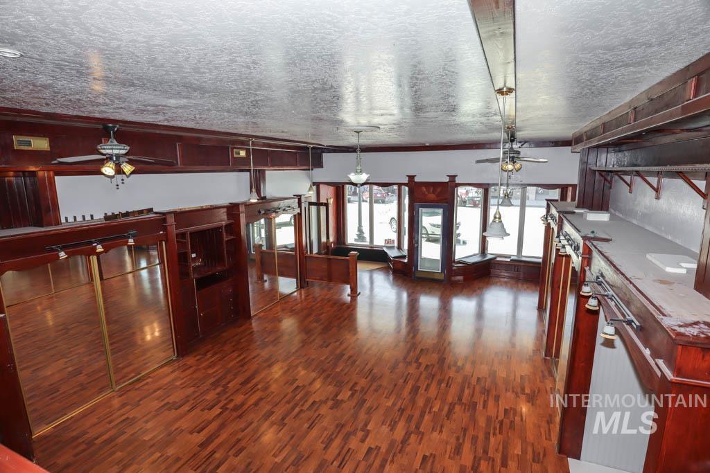 Kitchen with ceiling fan, dark wood-type flooring, decorative light fixtures, reddish brown cabinets, and crown molding