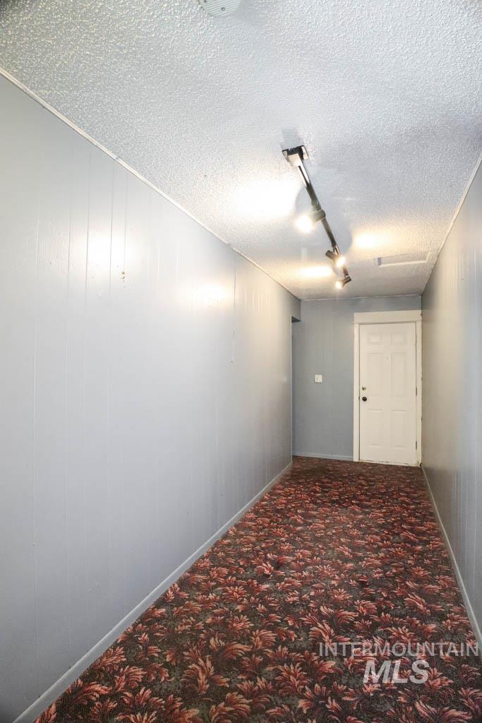 Hall featuring a textured ceiling, track lighting, and carpet flooring
