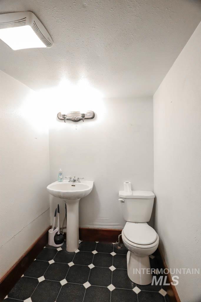 Half bathroom featuring a textured ceiling and dark flooring