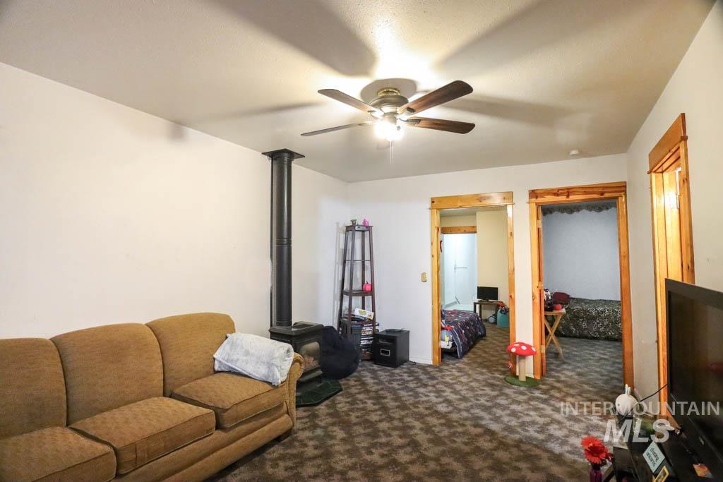 Living room with dark carpet, a wood stove, and a ceiling fan