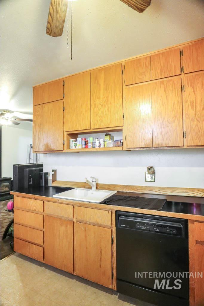 Kitchen featuring black dishwasher, a ceiling fan, open shelves, and brown cabinetry