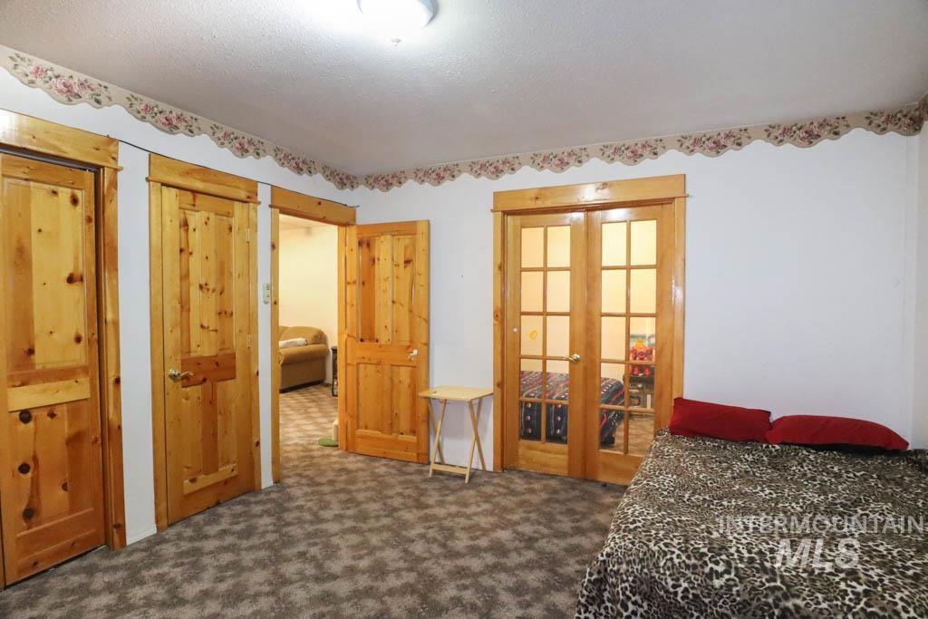 Bedroom featuring french doors, dark colored carpet, and a textured ceiling