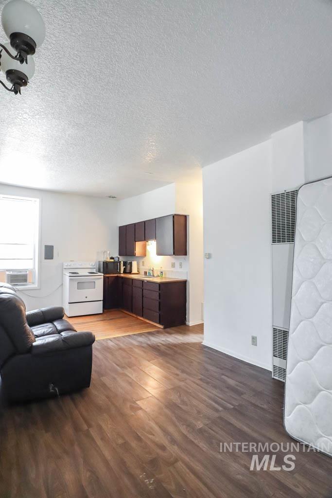 Living area featuring a textured ceiling, dark wood finished floors, and a heating unit