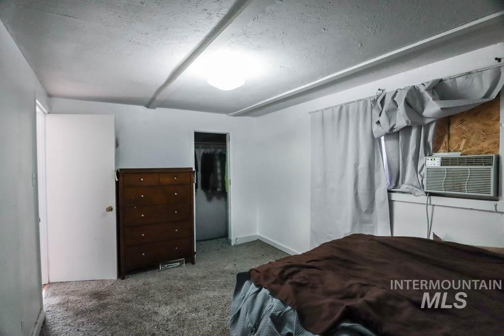 Bedroom featuring carpet floors, a closet, a textured ceiling, and cooling unit