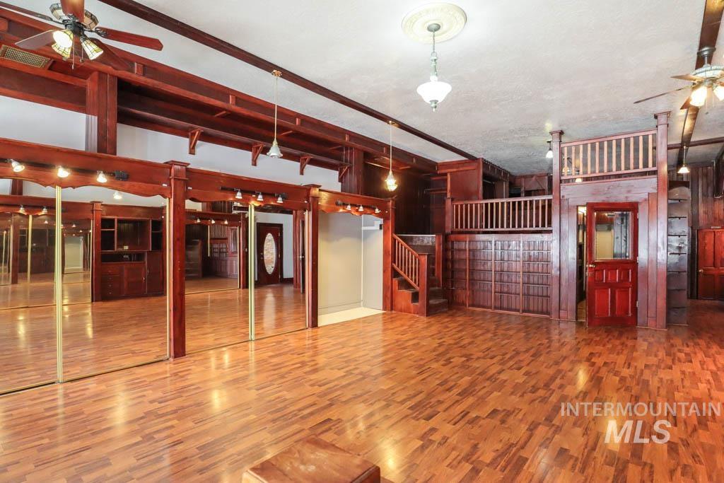 Miscellaneous room featuring ceiling fan, wood finished floors, stairway, and beamed ceiling