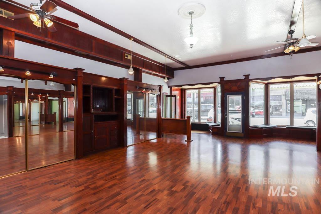 Unfurnished living room with ceiling fan and dark wood-style floors