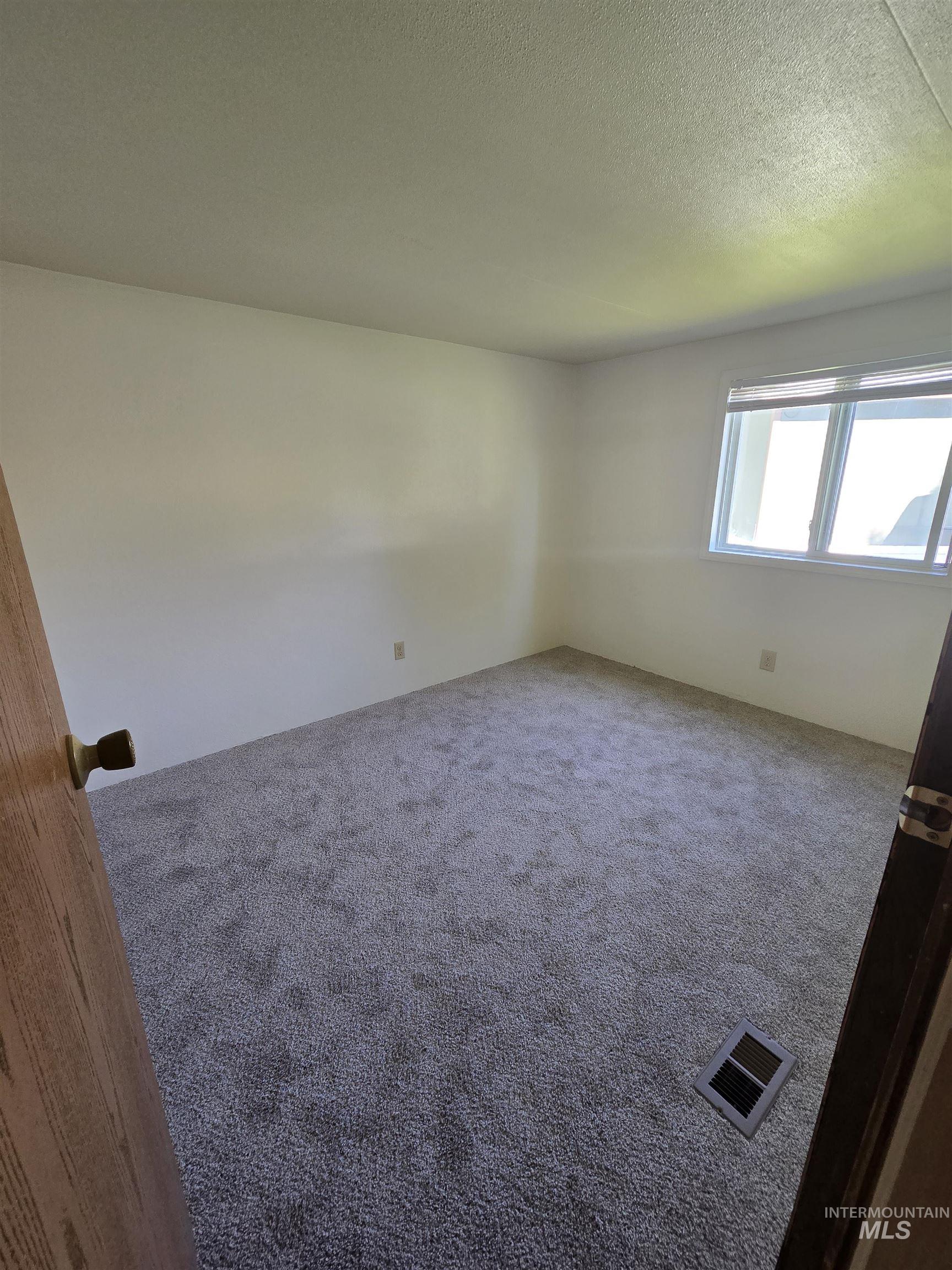 Carpeted empty room with a textured ceiling
