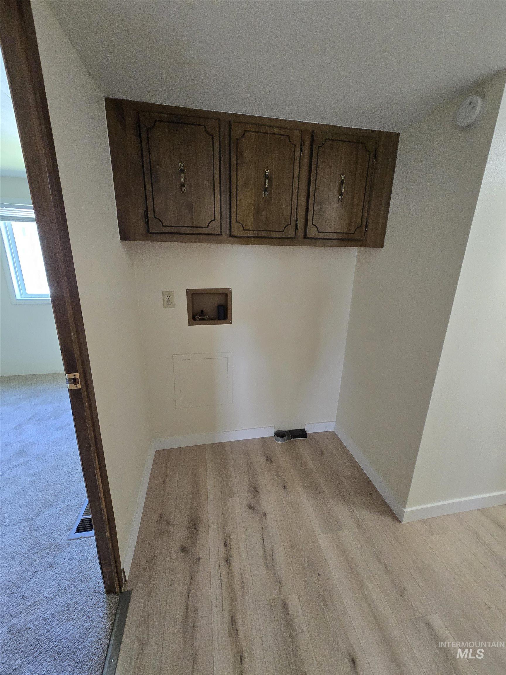 Laundry area featuring hookup for a washing machine, light wood-style floors, and cabinet space