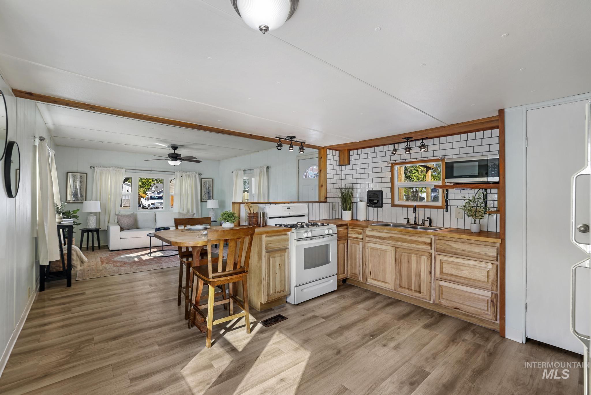 Kitchen featuring white range with gas stovetop, light wood-style floors, light brown cabinets, butcher block counters, and a peninsula