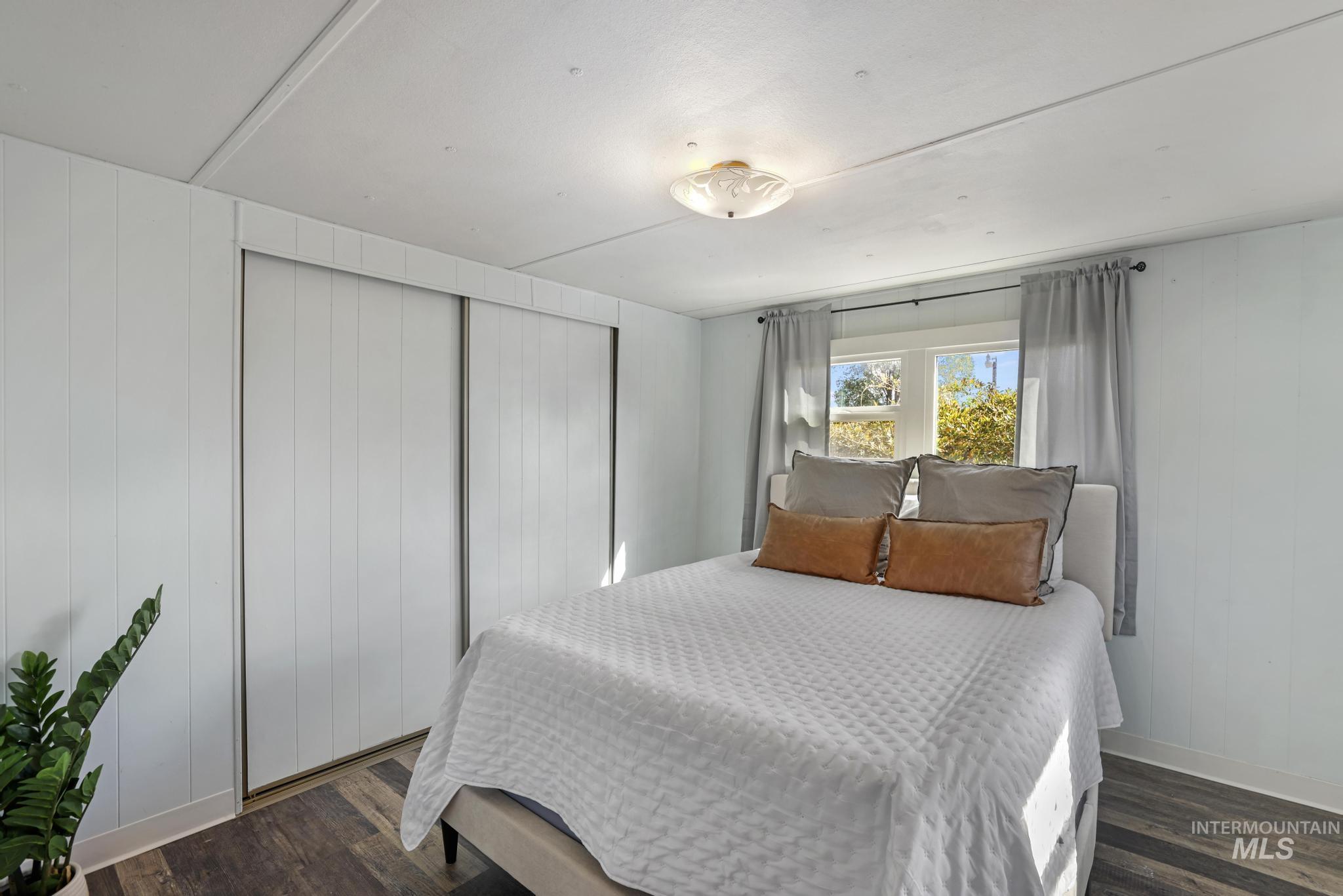 Bedroom featuring wooden walls and dark wood-type flooring