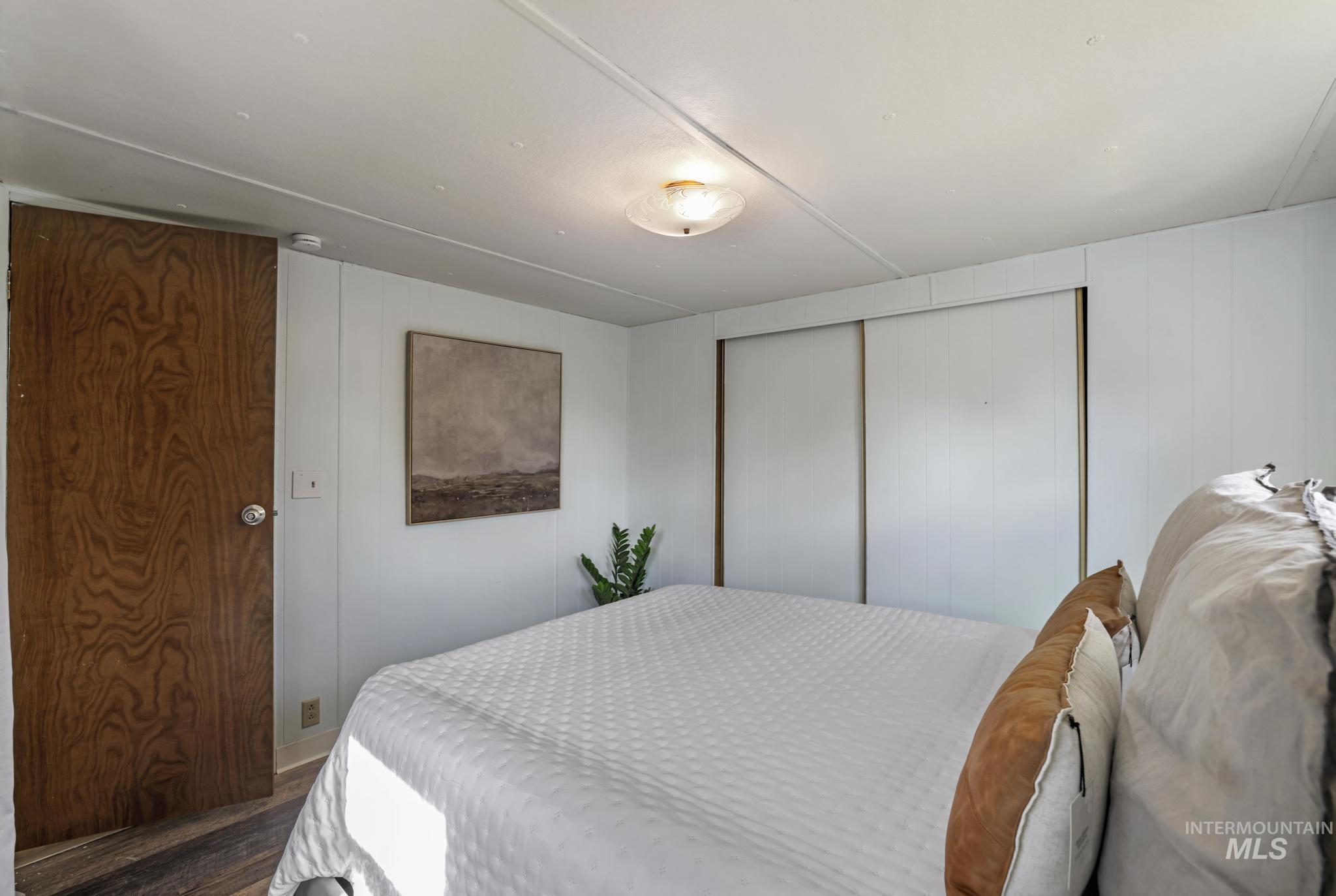 Bedroom with wood finished floors, a closet, and wooden walls