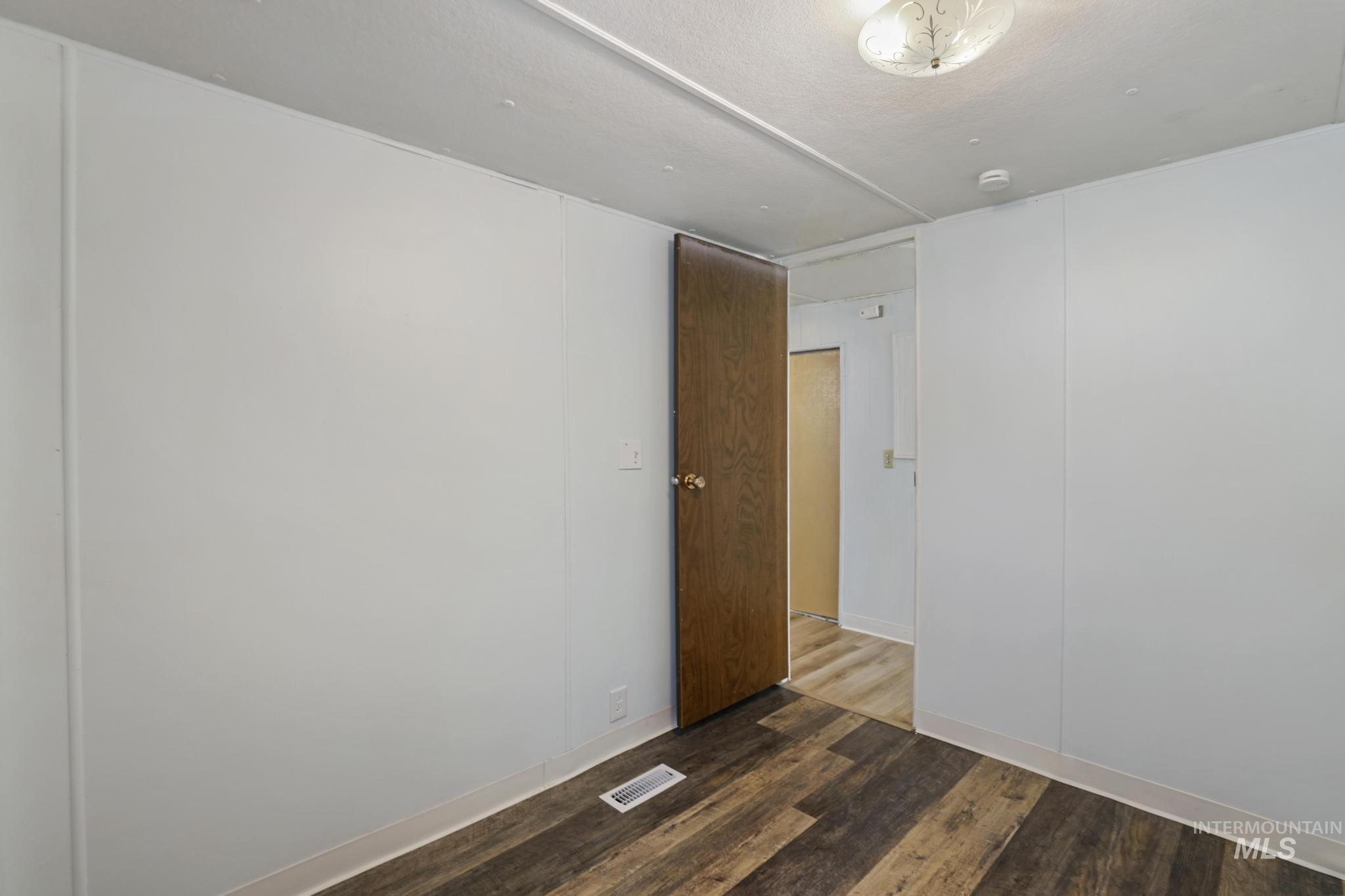 Unfurnished room featuring dark wood-type flooring and baseboards
