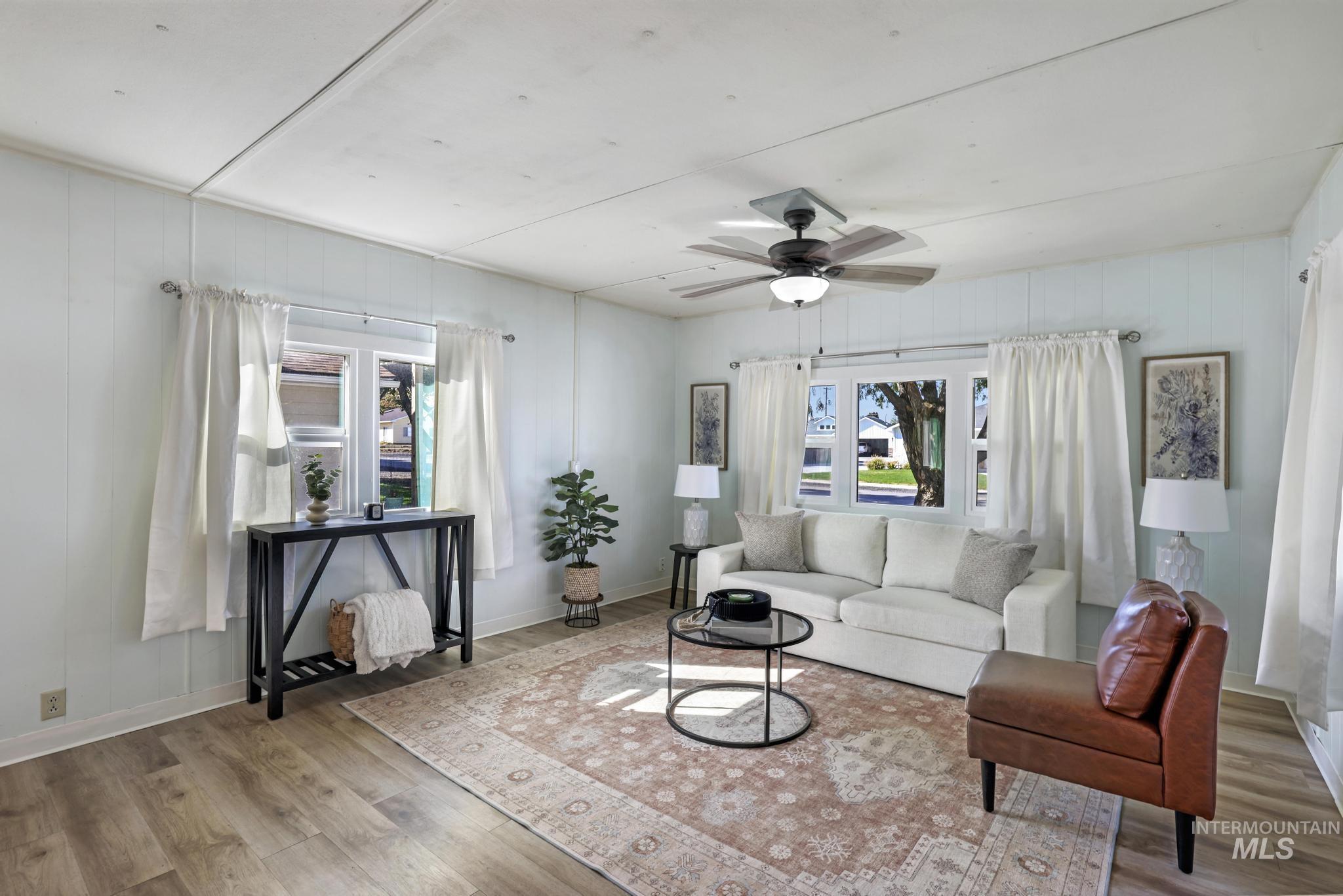 Living area with wood finished floors, ceiling fan, and wood walls
