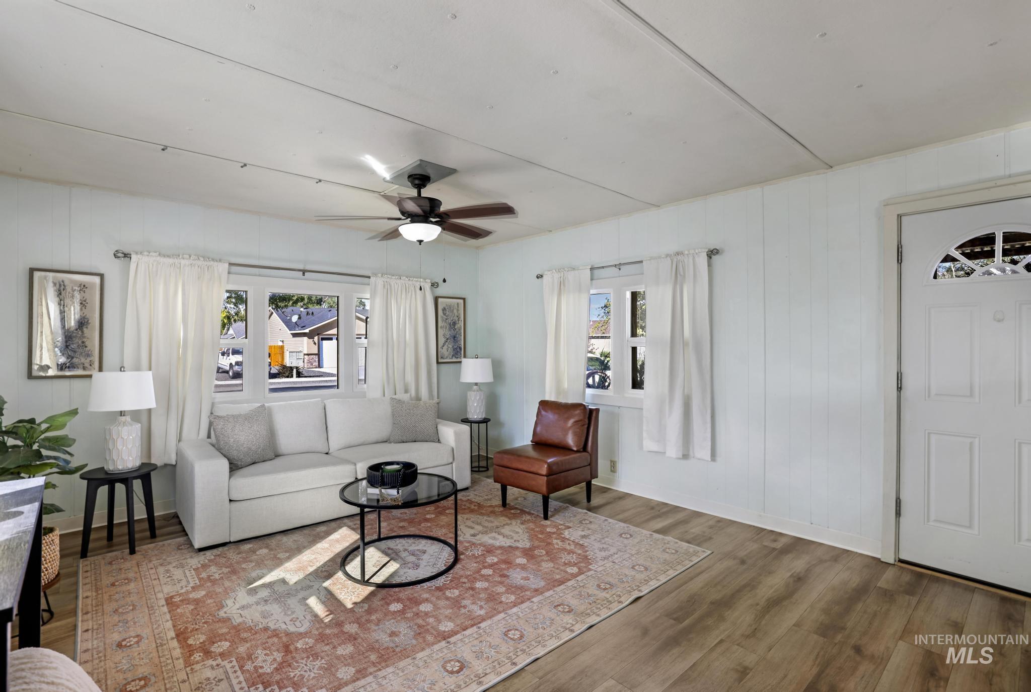 Living room featuring wood finished floors, wooden walls, and ceiling fan