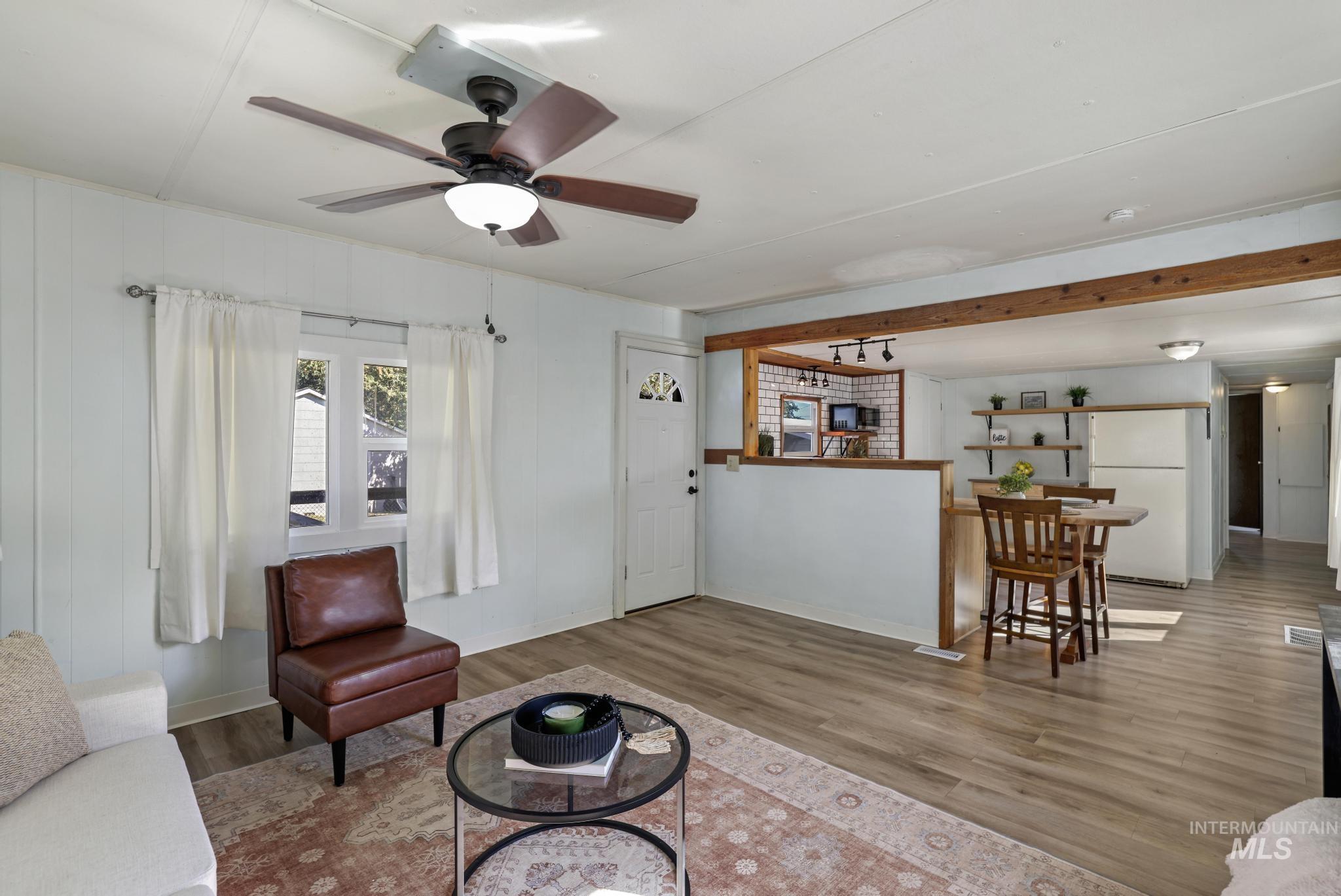 Living area featuring wood finished floors, ceiling fan, and beamed ceiling