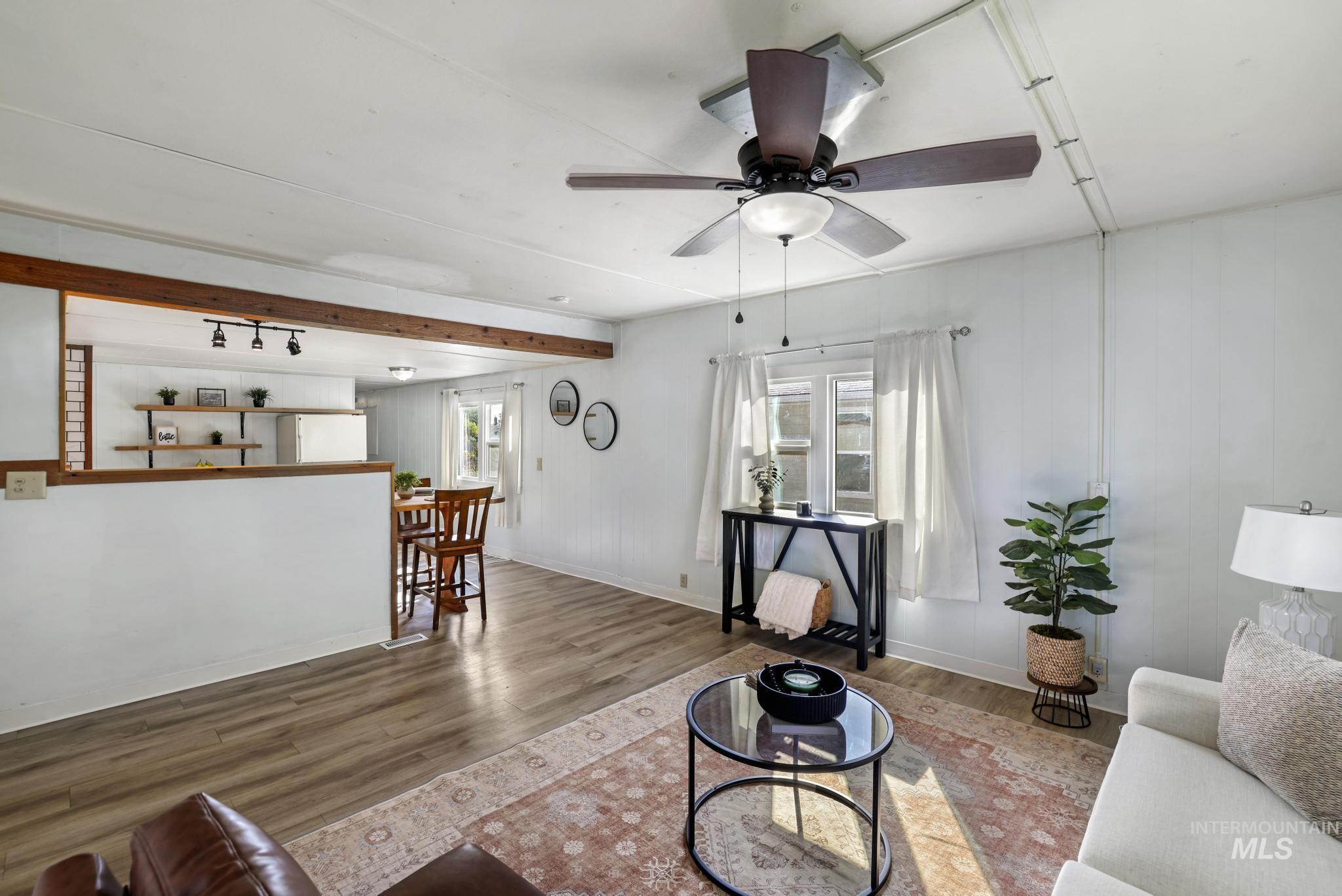 Living room with wood finished floors, a ceiling fan, and beam ceiling
