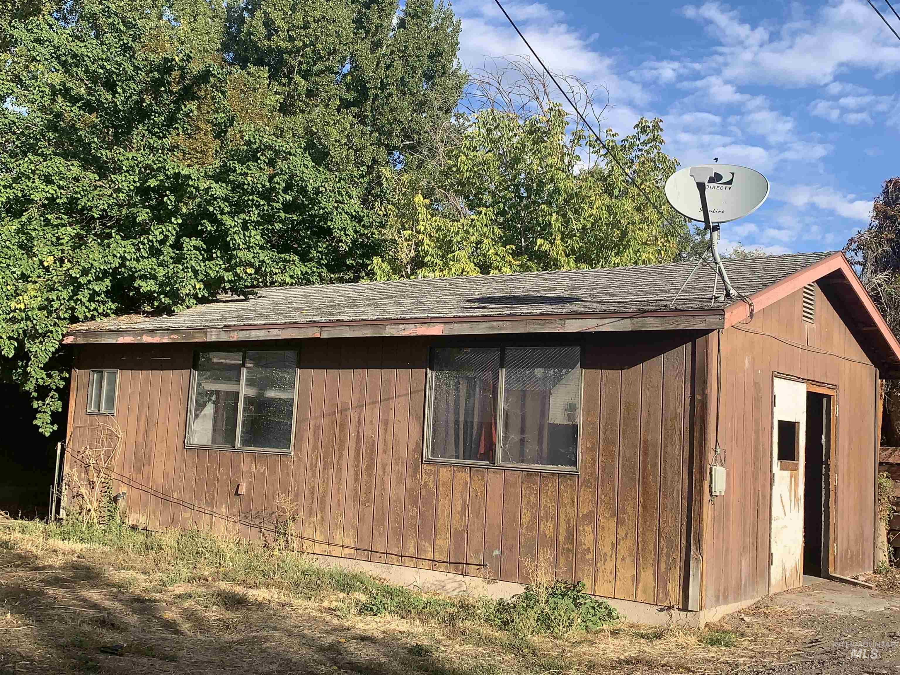 View of side of property with a shingled roof and an outbuilding