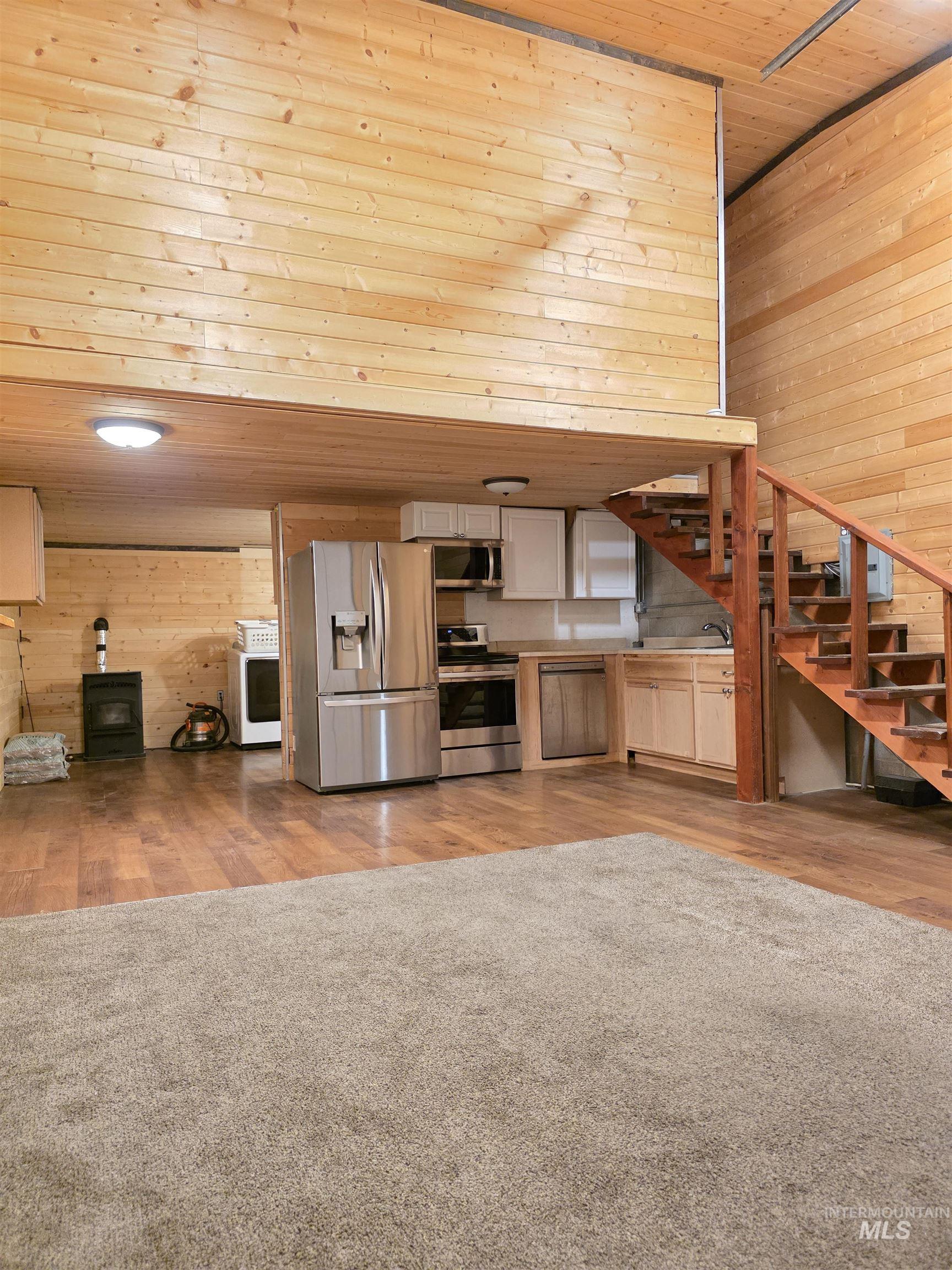 Kitchen featuring wood walls, stainless steel appliances, wooden ceiling, light wood-type flooring, and washer / clothes dryer