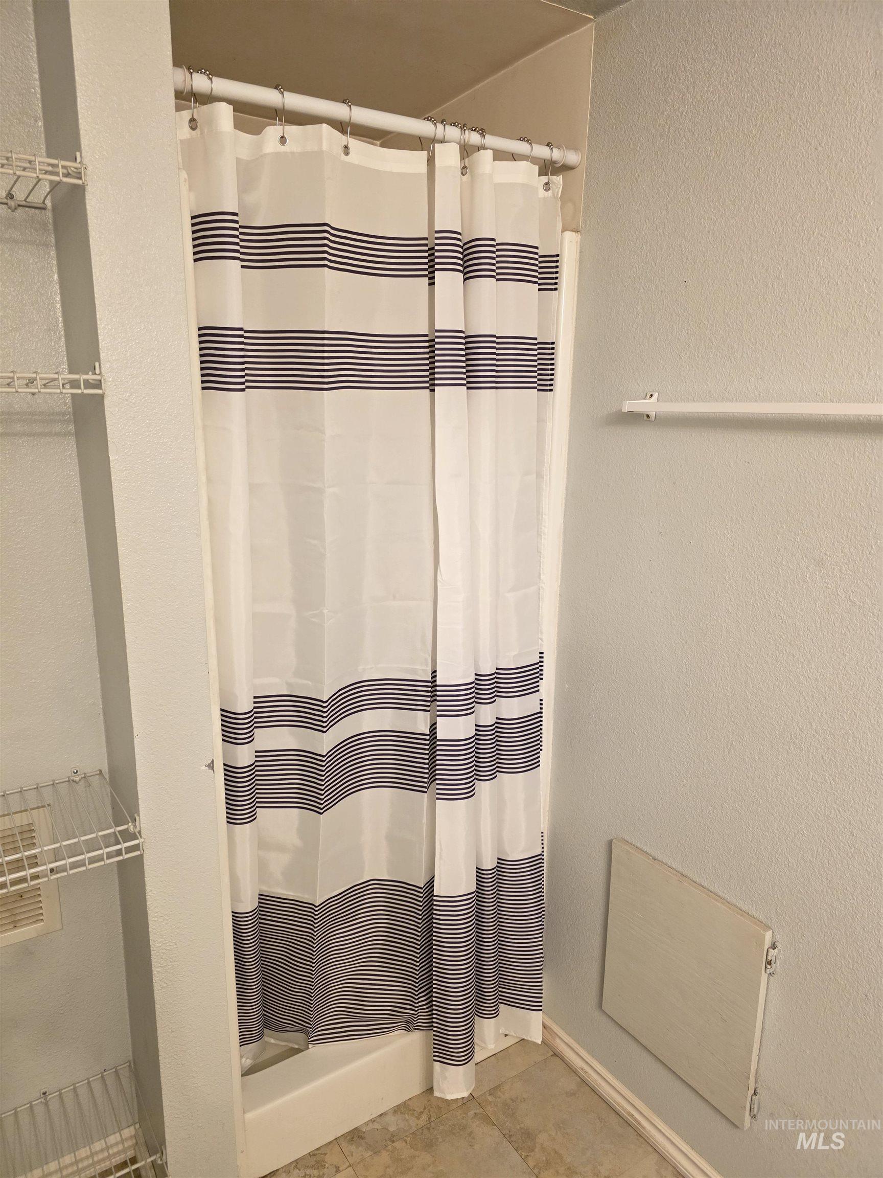 Bathroom featuring a textured wall and a shower stall