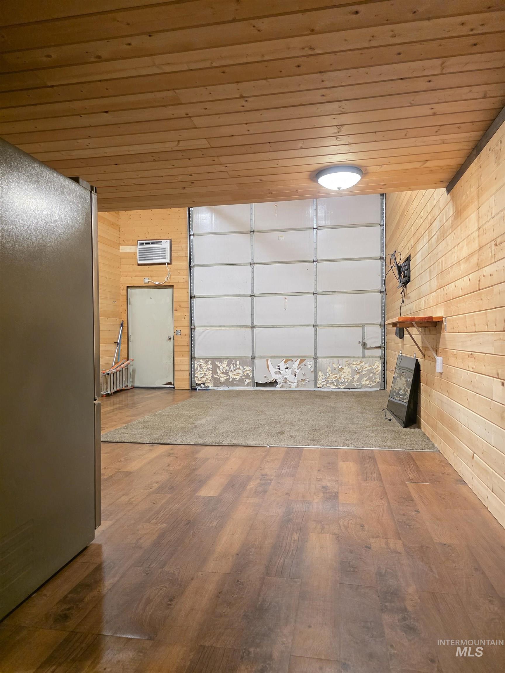 Garage with wooden walls, freestanding refrigerator, and wood ceiling
