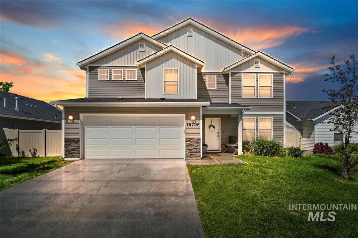 View of front of home featuring board and batten siding, stone siding, a garage, and concrete driveway