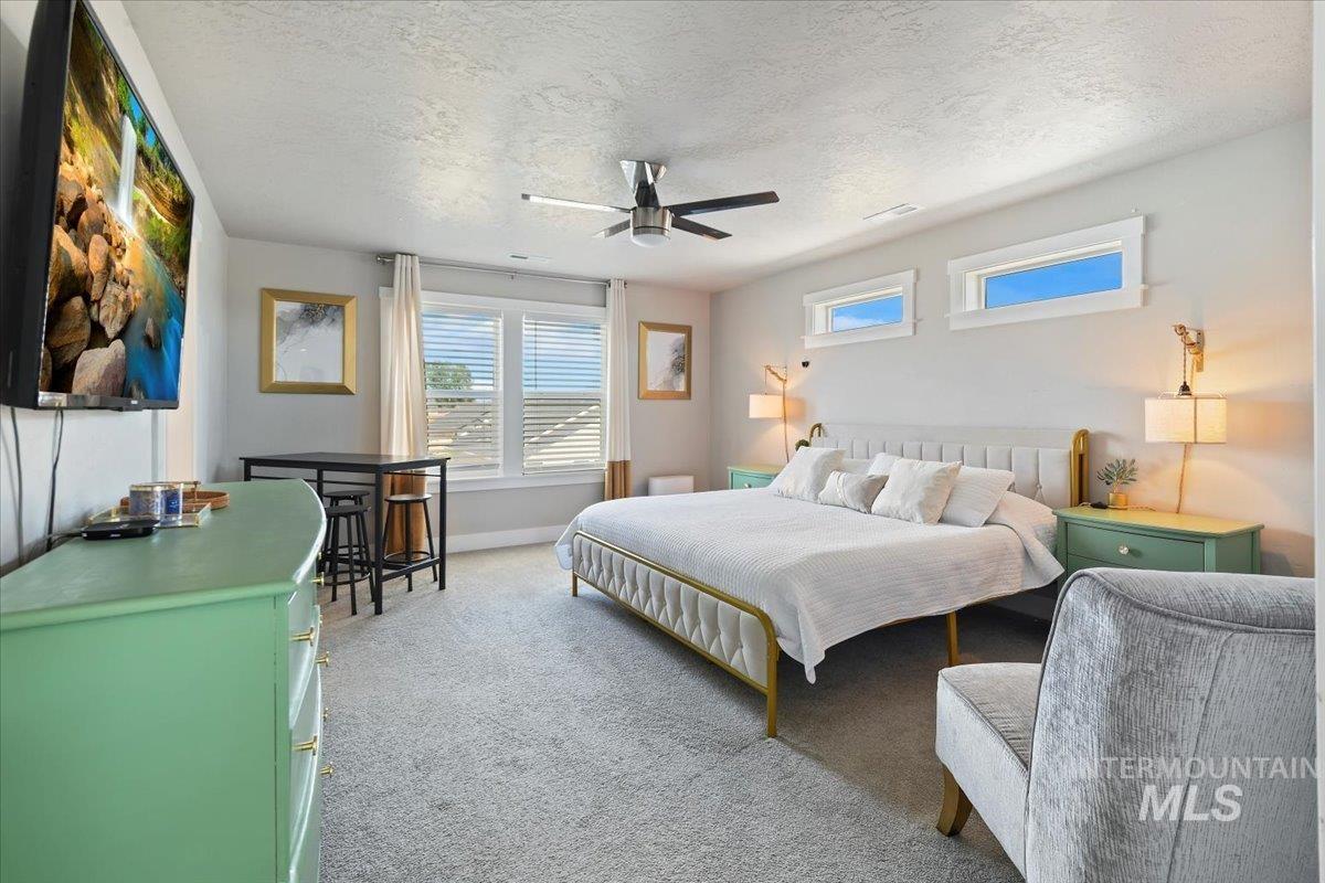 Bedroom with carpet floors, a textured ceiling, and a ceiling fan