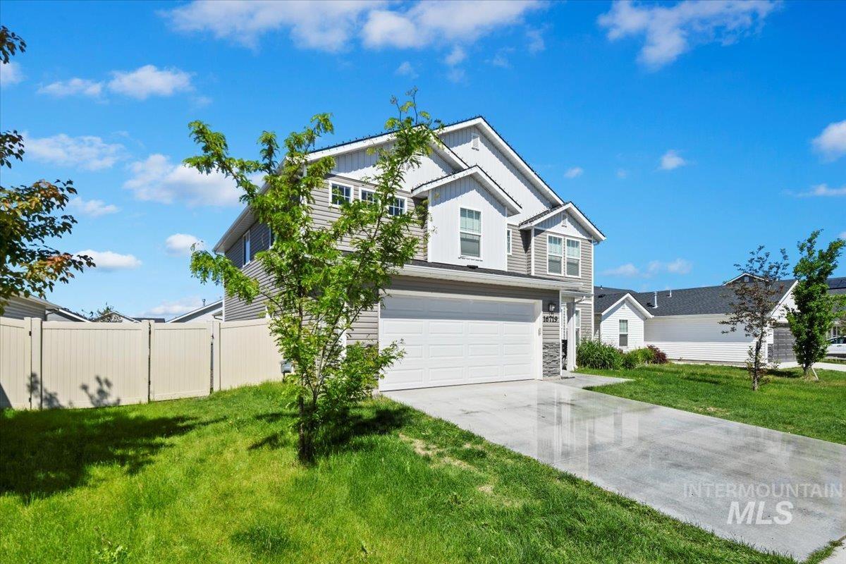 Traditional-style house featuring board and batten siding, an attached garage, driveway, and stone siding