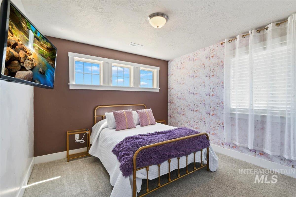 Carpeted bedroom featuring a textured ceiling and baseboards