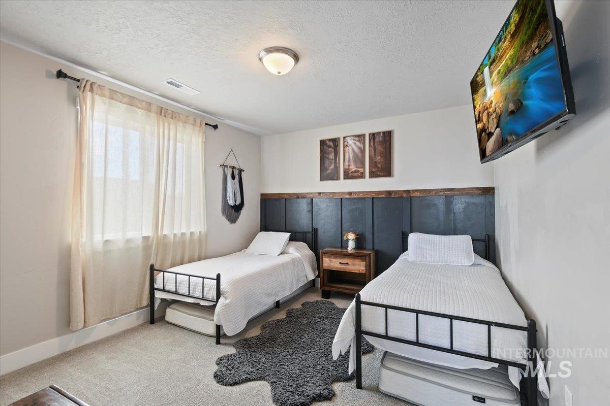 Carpeted bedroom featuring a textured ceiling and baseboards