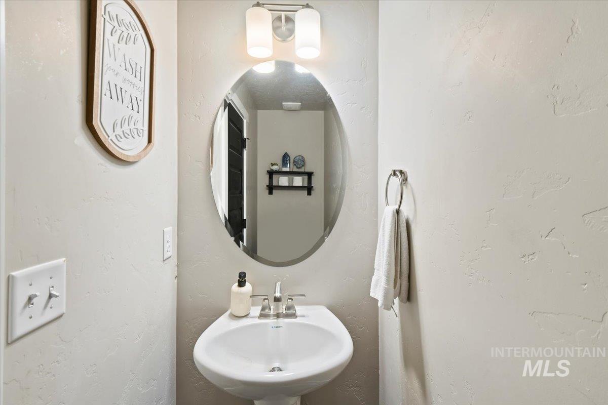 Half bath featuring a textured wall and a sink